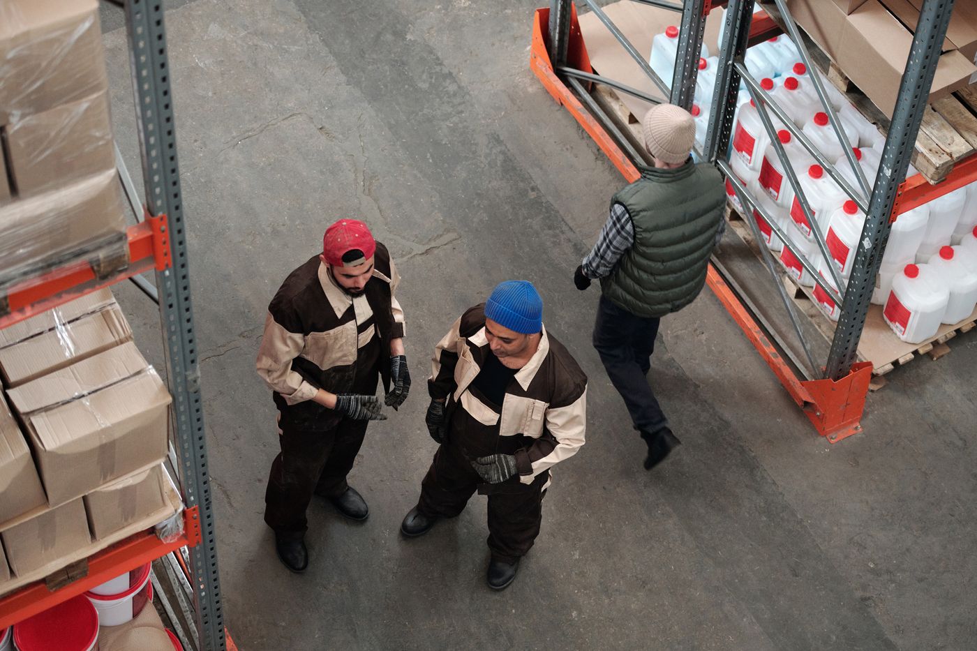 Warehouse workers coordinating among stocked shelves