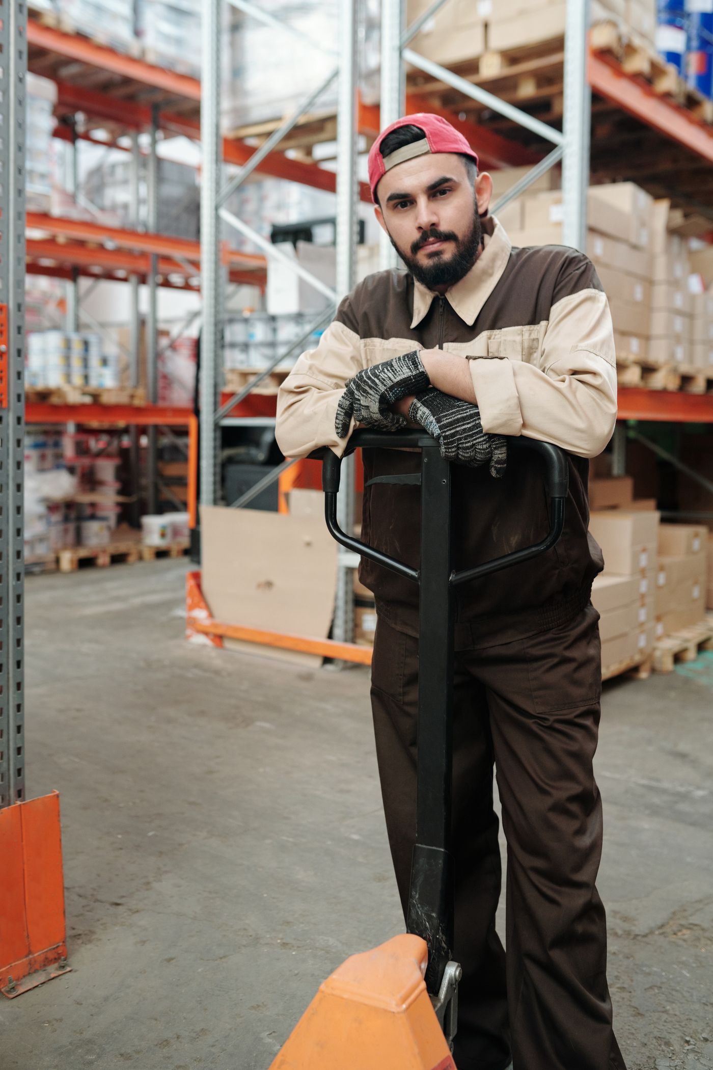 Warehouse worker guiding a pallet jack through an aisle
